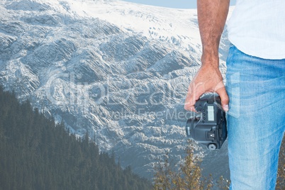 Half part of a man holding a camera in front of snow-covered mountains