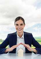 House under woman's protective hands with sky