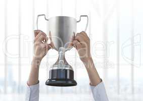 Business hand holding trophy against window