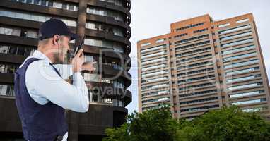 Security guard pointing at buildings while talking on walkie talkie