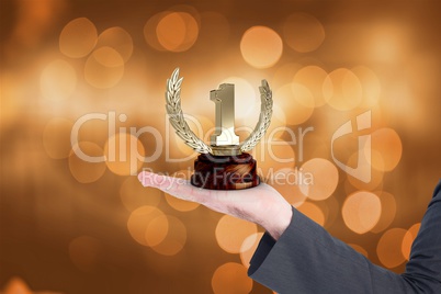 Businessman holding trophy against orange glowing background