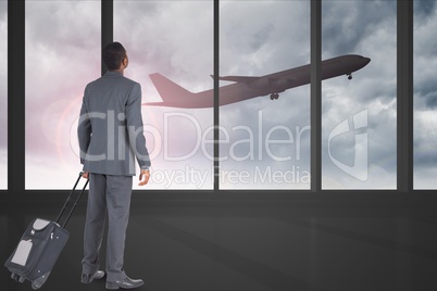 Businessman in airport watching the take-off of an airplane