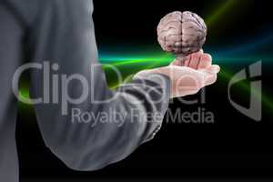 Business man holding a brain on his hand against black background