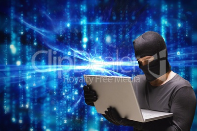 Cyber criminal wearing hood using a laptop against blue abstract background