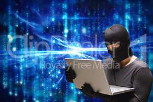 Cyber criminal wearing hood using a laptop against blue abstract background