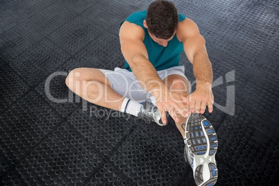 Athlete is stretching on black floor