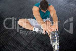 Athlete is stretching on black floor