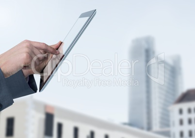 Businessman holding tablet in front of buildings