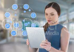 Businesswoman holding tablet with apps icons in bright space hall