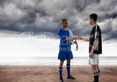 Soccer players in the beach giving the hands with clouds on the sky