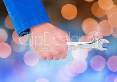 Mechanic Hand holding spanner with sparkling light bokeh background