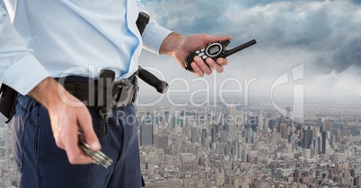 Security guard lower body with walkie talkie against skyline and clouds