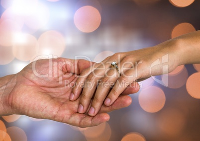 Couple Hands holding engagement wedding ring with sparkling light bokeh background