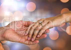 Couple Hands holding engagement wedding ring with sparkling light bokeh background