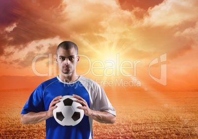 soccer player with ball on his hands in the sunset