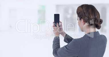 Businesswoman holding mobile phone in bright shopping mall