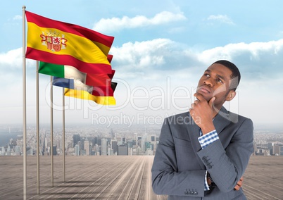 main language flags near young businessman thinking with city behind
