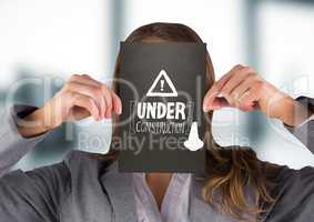 Business woman with black card over face showing white construction doodle against blurry grey offic