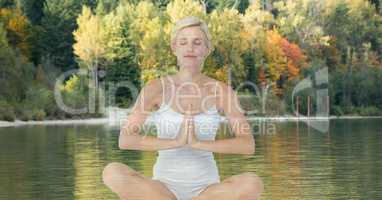 Woman doing yoga in front of a lake and wood