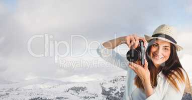 Hipster clicking photographs by snowcapped mountains against sky