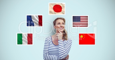 Thoughtful smiling woman standing by flags against blue background