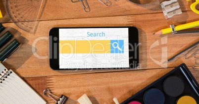 Directly above shot of smart phone with search text surrounded with office equipment