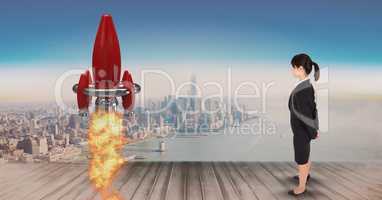 Digital composite image of businesswoman standing on pier and watching rocket launch against city