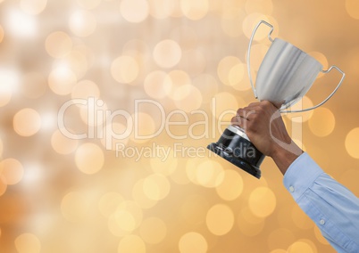 Business hand holding trophy against defocused lights