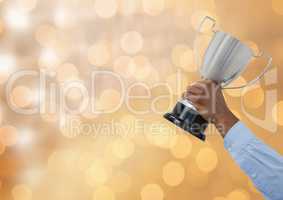 Business hand holding trophy against defocused lights