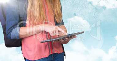 Woman mid section with backpack and tablet against sky and flare