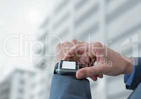 Businessman holding watch against buildings