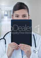 Doctor holding tablet over face in corridor