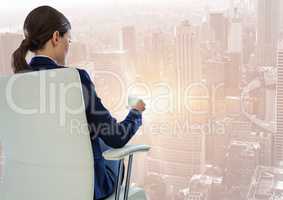Back of seated business woman drinking against blurry city with flare