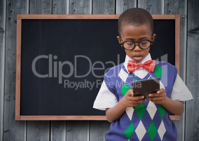 Boy in vest and bowtie with calculator against chalkboard and grey wood panel