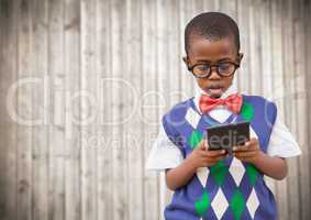 Boy in vest and bowtie with calculator against blurry wood panel