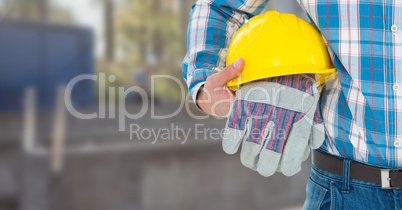 Construction Worker with safety gloves and hat in front of construction site
