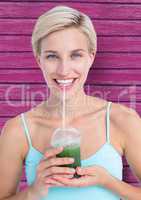 fitness woman taking a healthy juice with pink wood background