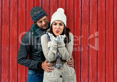 couple: she sending a kiss and he looking she with red wood background