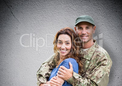 soldier and wife smiling. concrete wall