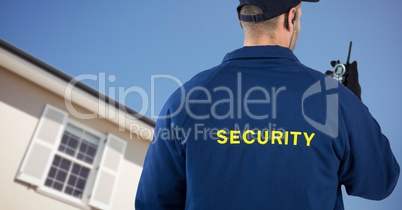 Security man in front of a house holding a talkie-walkie