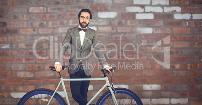 Reflecting hipster man with a bike in front of red stone wall