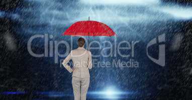 Rear view of businesswoman holding red umbrella standing in rain