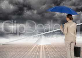 Digital image of businesswoman holding blue umbrella and briefcase while looking at seesaw standing
