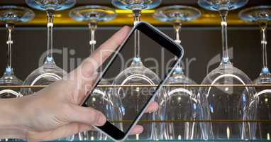 Hand photographing upside down wine glasses through smart phone