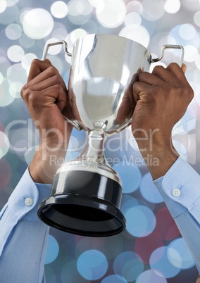 Hands holding trophy cup with sparkling light bokeh background