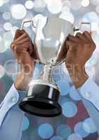 Hands holding trophy cup with sparkling light bokeh background