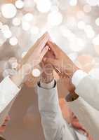 Hands of teamk together reaching with sparkling light bokeh background
