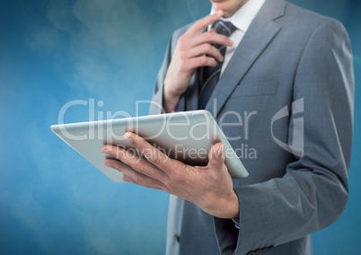Businessman holding tablet against blue foggy background