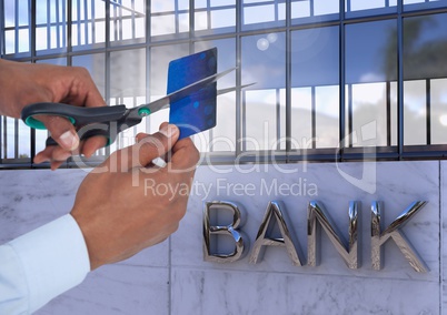 Hands cutting bank card next to bank