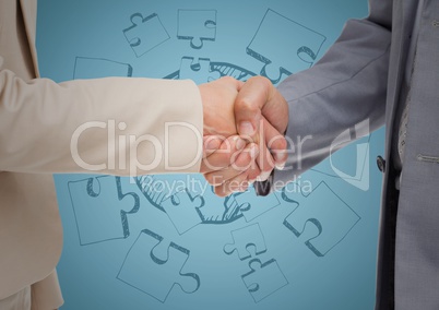 Close up of handshake against blue jigsaw doodle and blue background